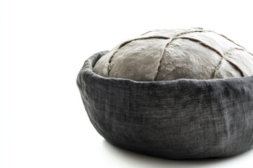 Obraz premium A round loaf of sourdough bread rests in a dark gray linen bread basket.
