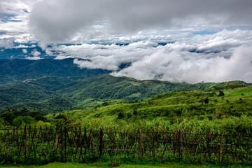 The natural background of the sky above several large mountains, with a view of clouds, trees, mist and a cool breeze blowing throughout the journey.