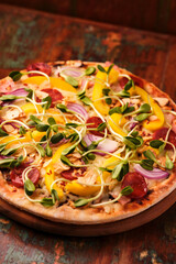 Pizza with chorizo ​​sausage, mozzarella cheese and yellow pepper. Rustic wooden background. Soft focus.	