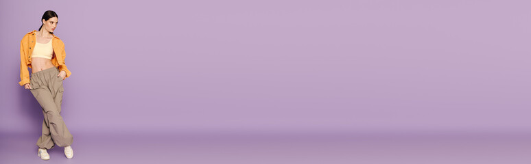 A beautiful young woman showcases her unique style while standing against a pastel backdrop.