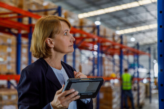 Thoughtful manager standing with tablet PC in warehouse