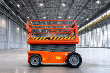 Orange scissor lift in spacious industrial warehouse with high ceilings and bright lighting