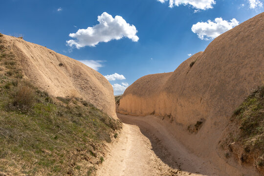 a soil path with a narrow cliff each side of it on a cloudy day