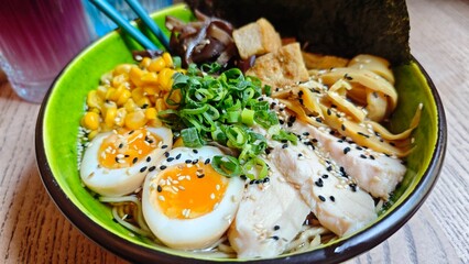 Colorful bowl of ramen with eggs, corn, chicken, tofu, mushrooms and scallions