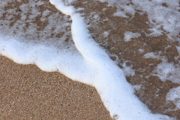 sea foam shaped as Y on the sand of the beach