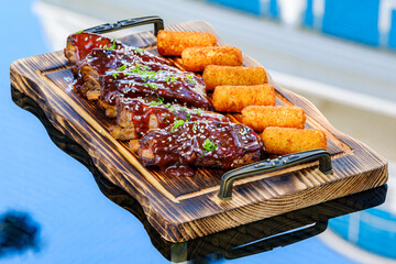 Tantalizing BBQ ribs, glazed with succulent sauce and sesame, served alongside potato croquettes on...