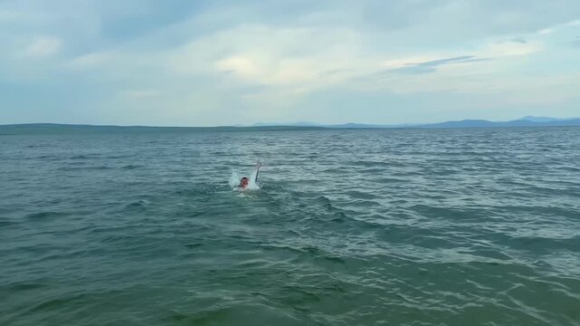 A man swims in Bukhtarma reservoir, east Kazakhstan. The guy is enjoying a vacation by the sea. Travel and freedom. Tourism and adventure