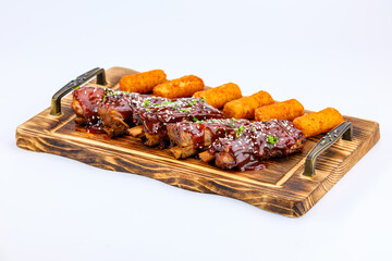 Tantalizing BBQ ribs, glazed with succulent sauce and sesame, served alongside potato croquettes on...