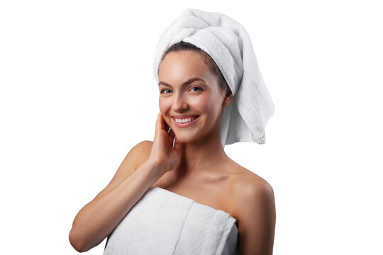 Smiling young woman applying facial cream under her eyes, wrapped in a white towel with a towel turban on her head. PNG with transparency	