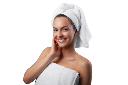 Smiling young woman applying facial cream under her eyes, wrapped in a white towel with a towel turban on her head. PNG with transparency	