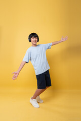 Young person enjoying music with arms wide open and wearing headphones on a yellow background