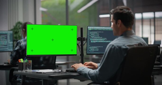 Software Developer Working on Computer with Green Screen Mock Up Display, Writing Source Code for an App in Office. IT Programming Department Researching and Developing Online Software