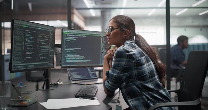 Female Software Developer in Glasses, Working on Desktop Computer, Writing Code and Managing Projects for a Corporate IT Partner. Girl Leaning In Closer to the Screen while Thinking