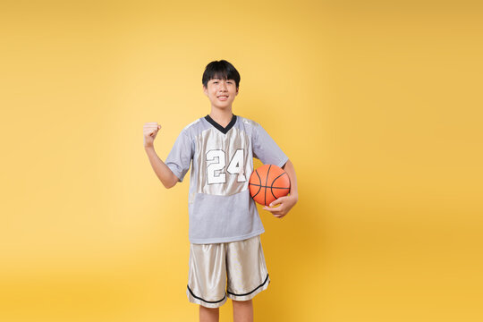 Enthusiastic youth in basketball attire celebrating a win against a sunny yellow backdrop