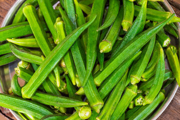 Lady Fingers or Okra over wooden table background. Raw Green Organic Okra Harvest Ready to Cook With. Close up Farm fresh okro on wooden rustic table.