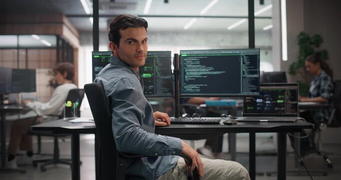 Portrait of a Young Handsome Software Engineer Turning to Look at a Camera, Pausing From Using a Desktop Computer in Office. Successful Information Technology Manager Working on Technology Projects