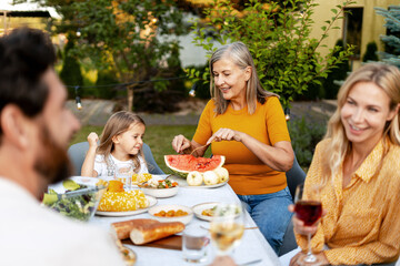 Happy family enjoying outdoor dinner in garden, together sitting at table, talking, thanksgiving day