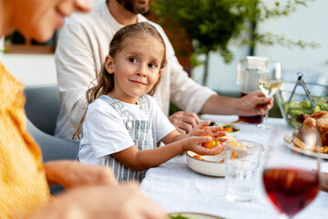 Smiling girl enjoying family dinner outdoors at home