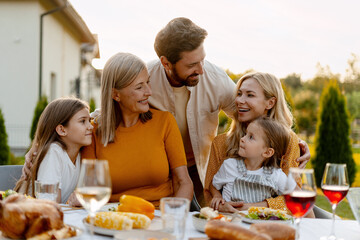 Happy family enjoying outdoor meal together in garden, having festive dinner, thanksgiving day