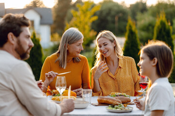 Happy family enjoying outdoor meal in backyard garden, festive table, celebration, thanksgiving day