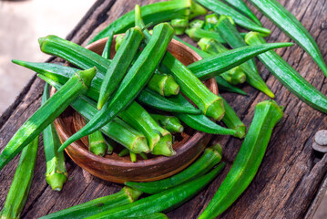 Lady Fingers or Okra over wooden table background. Raw Green Organic Okra Harvest Ready to Cook With. Close up Farm fresh okro on wooden rustic table.