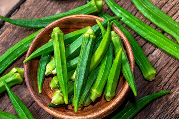 Lady Fingers or Okra over wooden table background. Raw Green Organic Okra Harvest Ready to Cook With. Close up Farm fresh okro on wooden rustic table.