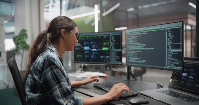 Thoughtful Female Engineer Working on Desktop Computer with Multiple Screens. Specialist in Research and Development Department Writing Software Code for an Advanced Neural Network Project