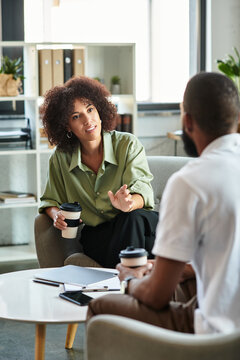 Modern office job interview between a young woman and man over coffee in an inviting space