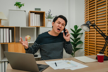 stressed man talking with smartphone. working with document and laptop at home office