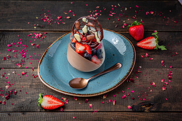 Delicate panna cotta or bird’s milk dessert with fresh berries on rustic brown wooden background.