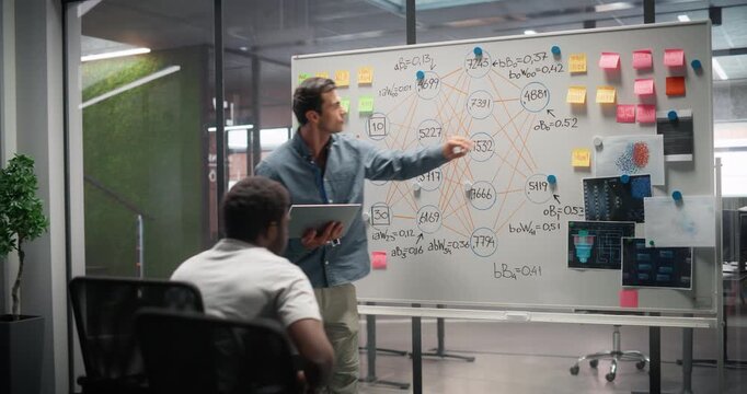 Caucasian and African IT Engineers Researching a Quantum Computer Concept, Making Technical Drawings on a Whiteboard and Discussing Computer Science Algorithms and Neural Network Structures