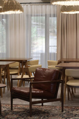 Cozy modern interior of a resort dining area at Bukhtarma Reservoir in early autumn. Wooden tables, leather chair and soft warm lighting create a relaxing atmosphere for guests