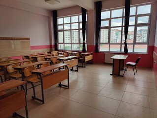 Empty classroom with wooden desks and large windows—symbolizing the quiet before learning, potential for knowledge, and the enduring space of education.