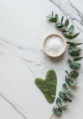 Clean Beauty Product Flatlay with Jade Gua Sha, Sea Salt, and Eucalyptus Branches on White Marble Surface