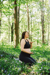 Fototapeta premium Pregnant woman doing fitness outdoors. Breathing and fitness for pregnant women. Healthy lifestyle concept