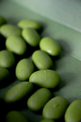 Several almond chocolates are oblong and coated with a smooth, glossy, green matcha layer.