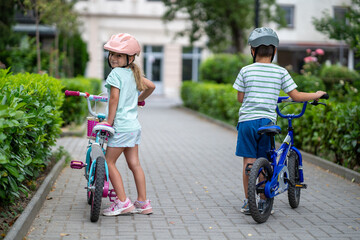 Two confident youngsters enjoy a bike ride in the city, showcasing their friendship and joy. The image highlights health and the importance of safety measures like wearing helmets. 