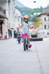 Cute girl wearing cycling helmet and riding bike at park. Portrait of a playful funny girl in a pink safety helmet on her bike