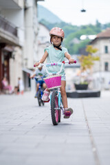 Cute girl wearing cycling helmet and riding bike at park. Portrait of a playful funny girl in a pink safety helmet on her bike