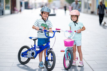 Two confident youngsters enjoy a bike ride in the city, showcasing their friendship and joy. The image highlights health and the importance of safety measures like wearing helmets. 