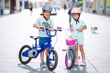 Two confident youngsters enjoy a bike ride in the city, showcasing their friendship and joy. The image highlights health and the importance of safety measures like wearing helmets. 