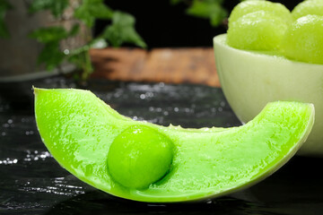 Fresh Honeydew Melon Slice with Water Droplets - Sweet Summer Fruit on Dark Surface © ThachThi