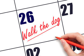 26 th day of the month.  Hand writing Walk the dog reminder and drawing a line on calendar with red...