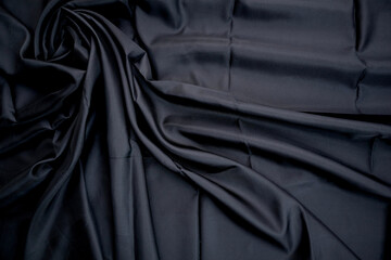 Dark Fabric with Elegant Folds. Abstract background of black silk fabric with soft, wavy folds.