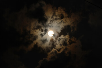 The sun during the day is surrounded by clouds with a dark and yellowish color concept, some of which appear to form a silhouette