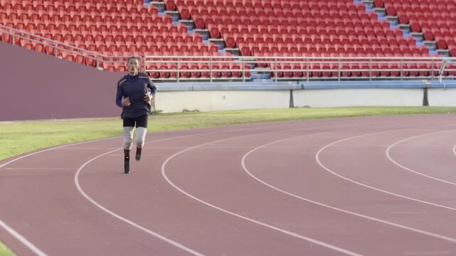 Person running on a track at a stadium in the afternoon with empty seats around