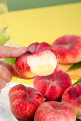 Fresh Shaanxi flat peaches with red skin and white flesh held in hand showing interior