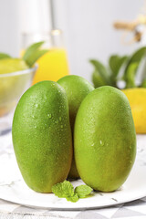 Fresh Green Mangoes with Water Droplets on White Plate - Tropical Fruit Still Life