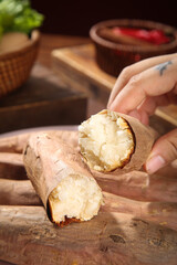 Hand holding freshly roasted chestnuts with white creamy flesh on wooden cutting board