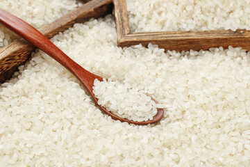 White rice grains in wooden spoon with bamboo basket - organic food ingredient